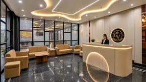 Ein Hotel-Empfangsbereich im modernen Stil, mit einer Rezeption, einer Sitzecke und großen Fenstern.