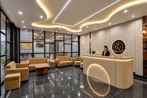 A hotel reception area with a modern design, featuring a reception desk, seating area, and large windows. - Hotel Grand Vista (Gorakhpur)