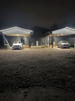 Un edificio con dos zonas de estacionamiento techadas, cada una con un automóvil dentro.