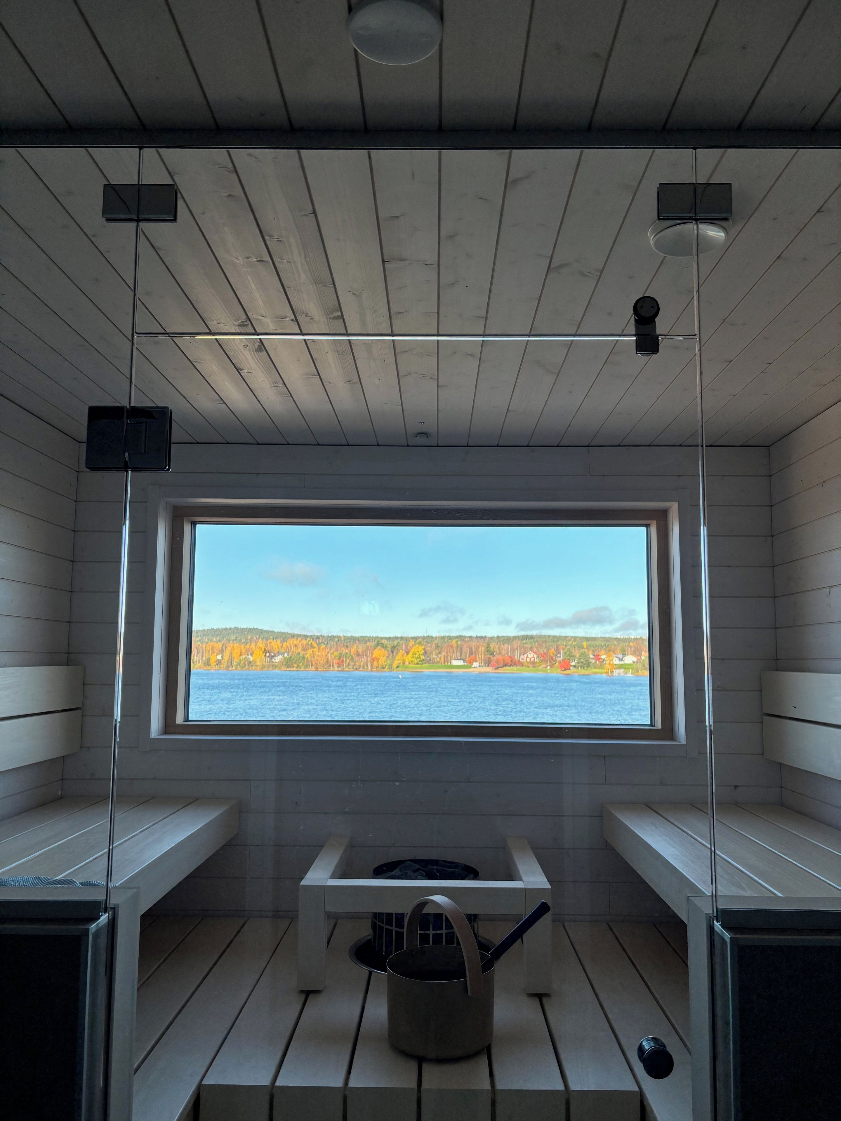 Un sauna avec des murs en bois, une grande fenêtre et un banc.