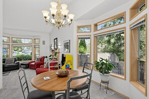 A spacious room with a dining table, chairs, a red sofa, and a chandelier. - Pnw Home With Sundance Hot Tub 3 Bedroom Home (Bonney Lake)