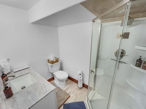 Uma casa de banho com lavatório de mármore, sanita e cabine de duche com parede de vidro.