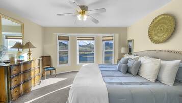 A bedroom with a bed, dresser, chair, and a ceiling fan.