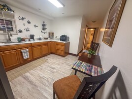 A kitchen with wooden cabinets, a dining table with chairs, and a wall with coffee and tea bar decor.