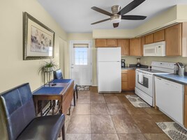 A compact kitchen with a refrigerator, microwave, stove, and a ceiling fan.