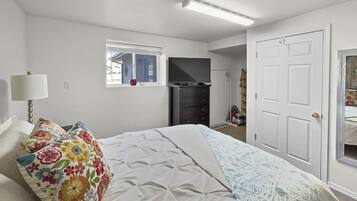 A bedroom with a bed, a dresser, a television, and a window.