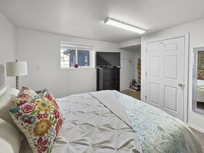 A bedroom with a bed, a dresser, a television, and a window. - Forever Family Farm 3 Bedroom Home (Montrose)