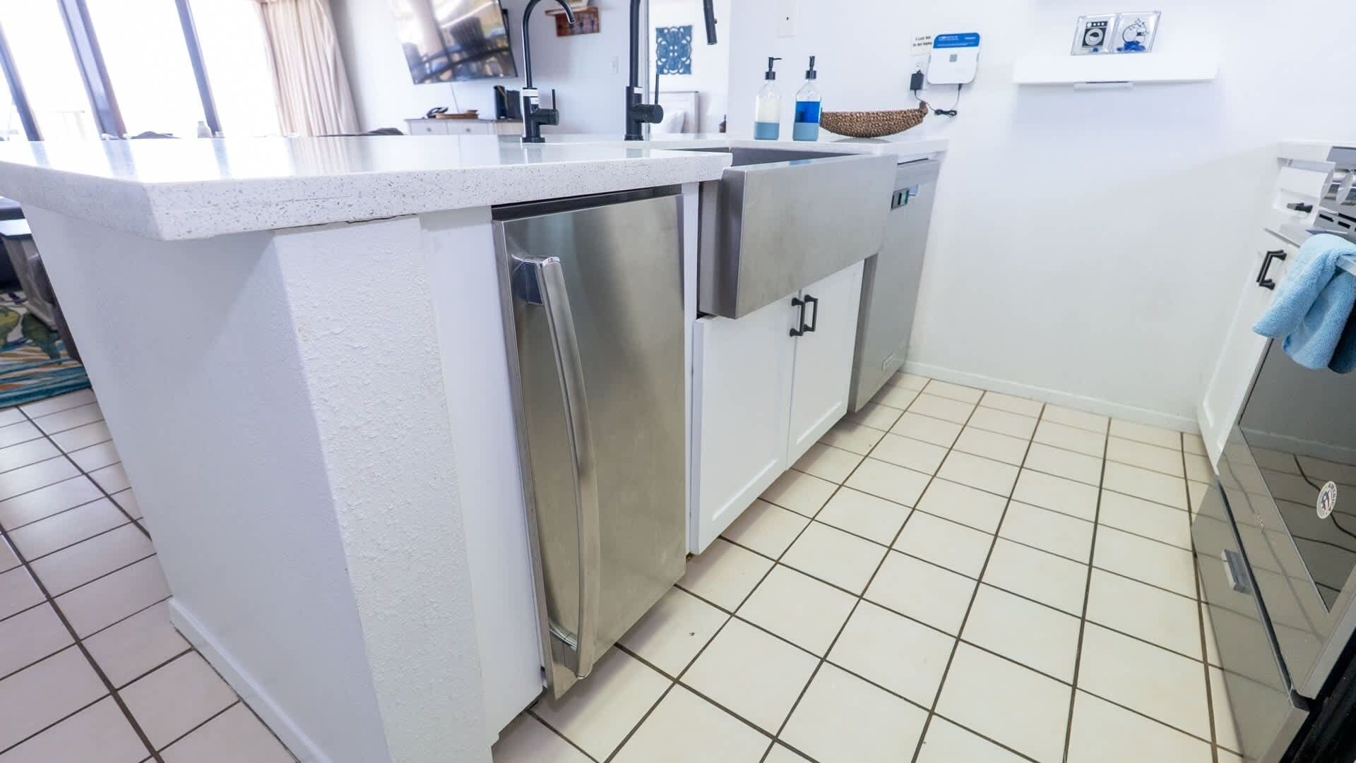 Cozinha com armários brancos, eletrodomésticos de aço inoxidável e piso revestido de azulejos.