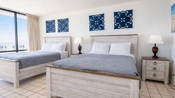 A hotel room with two beds, a large window, and decorative wall art.
