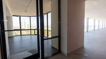 A spacious interior with large windows offering a view of a beach and high-rise buildings.