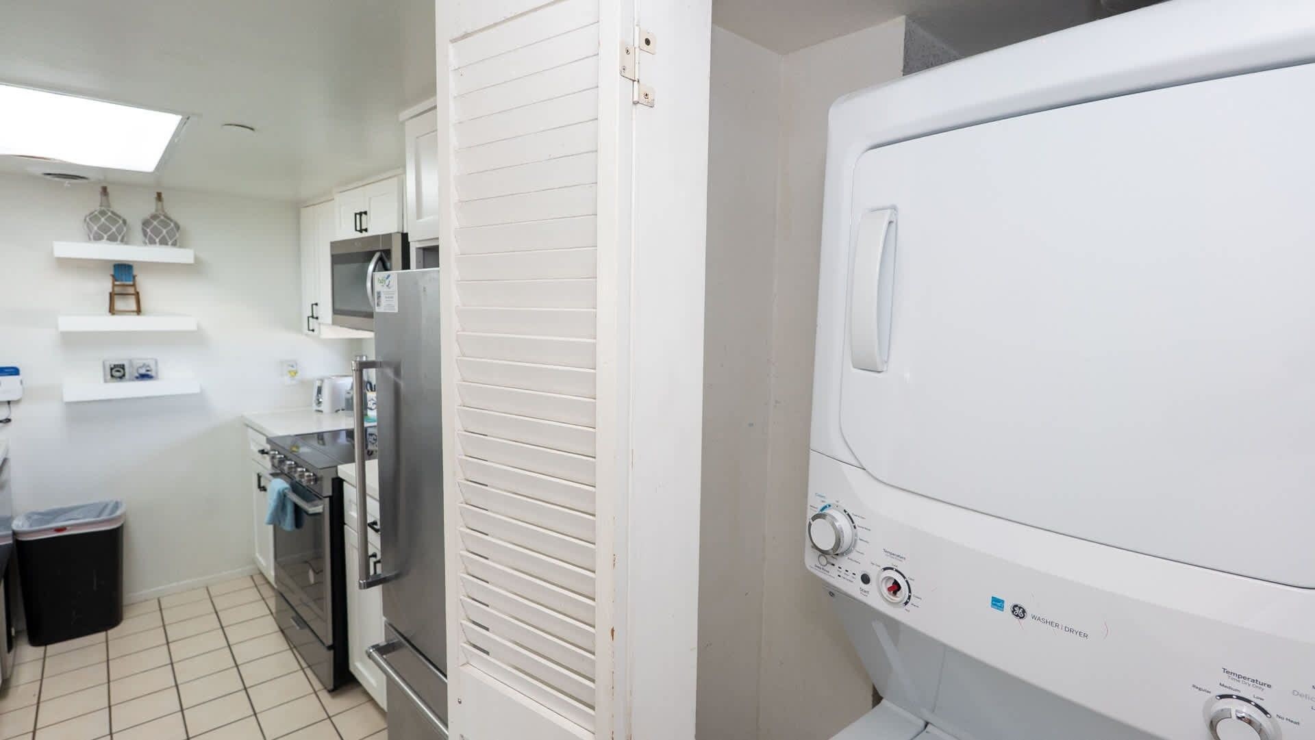 A compact kitchen with a refrigerator, microwave, oven, and a washing machine.