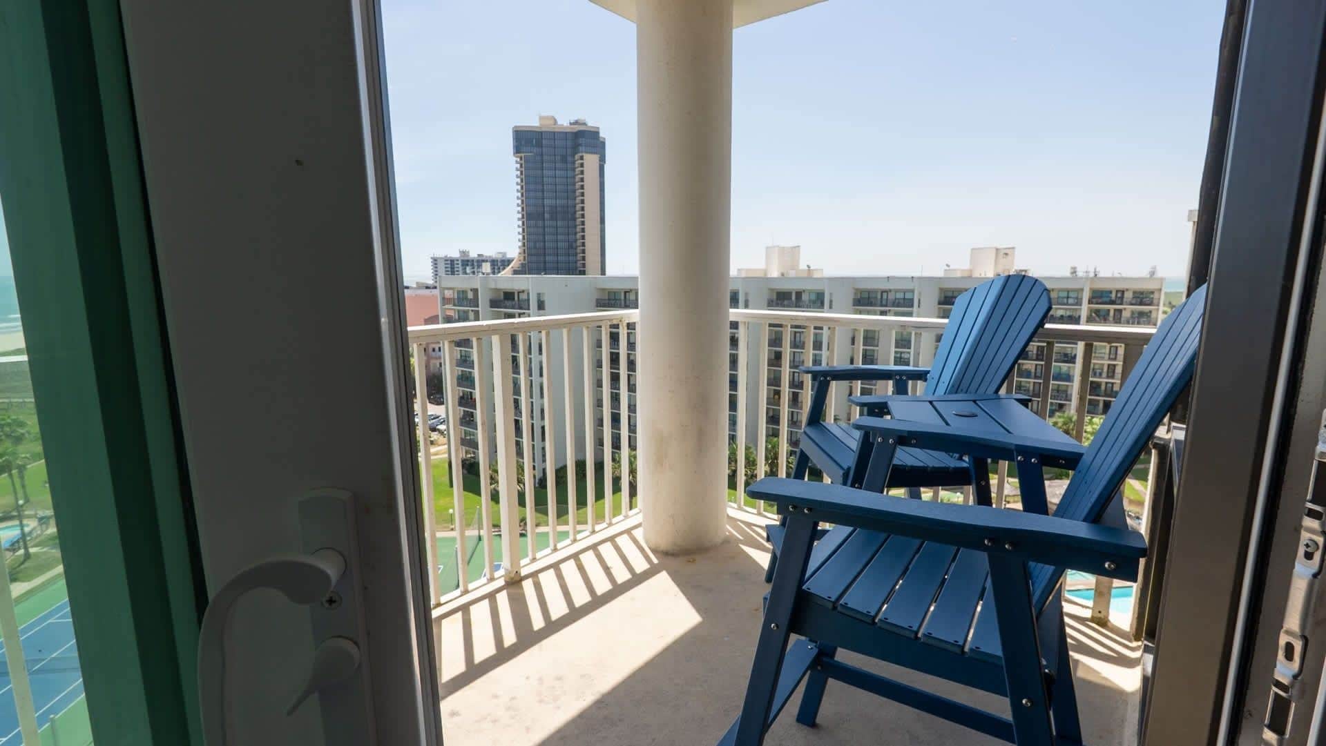 Varanda com mesa e duas cadeiras, vista para um horizonte urbano com edifícios modernos.
