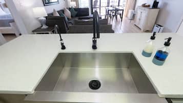 Una cocina moderna con un lavamanos de acero inoxidable, dos grifos y una encimera con dos dispensadores de jabón.