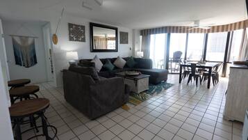 A living room with a sofa, coffee table, and dining area with chairs.