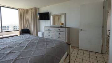 Una camera d'albergo con un letto, una cassettiera, una televisione e una finestra con tende.