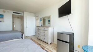 A bedroom with a bed, dresser, mirror, and a TV mounted on the wall. - Saida Royale, Beachfront 10th Floor, 2br, 3 Pools 2 Bedroom Apts (South Padre Island)