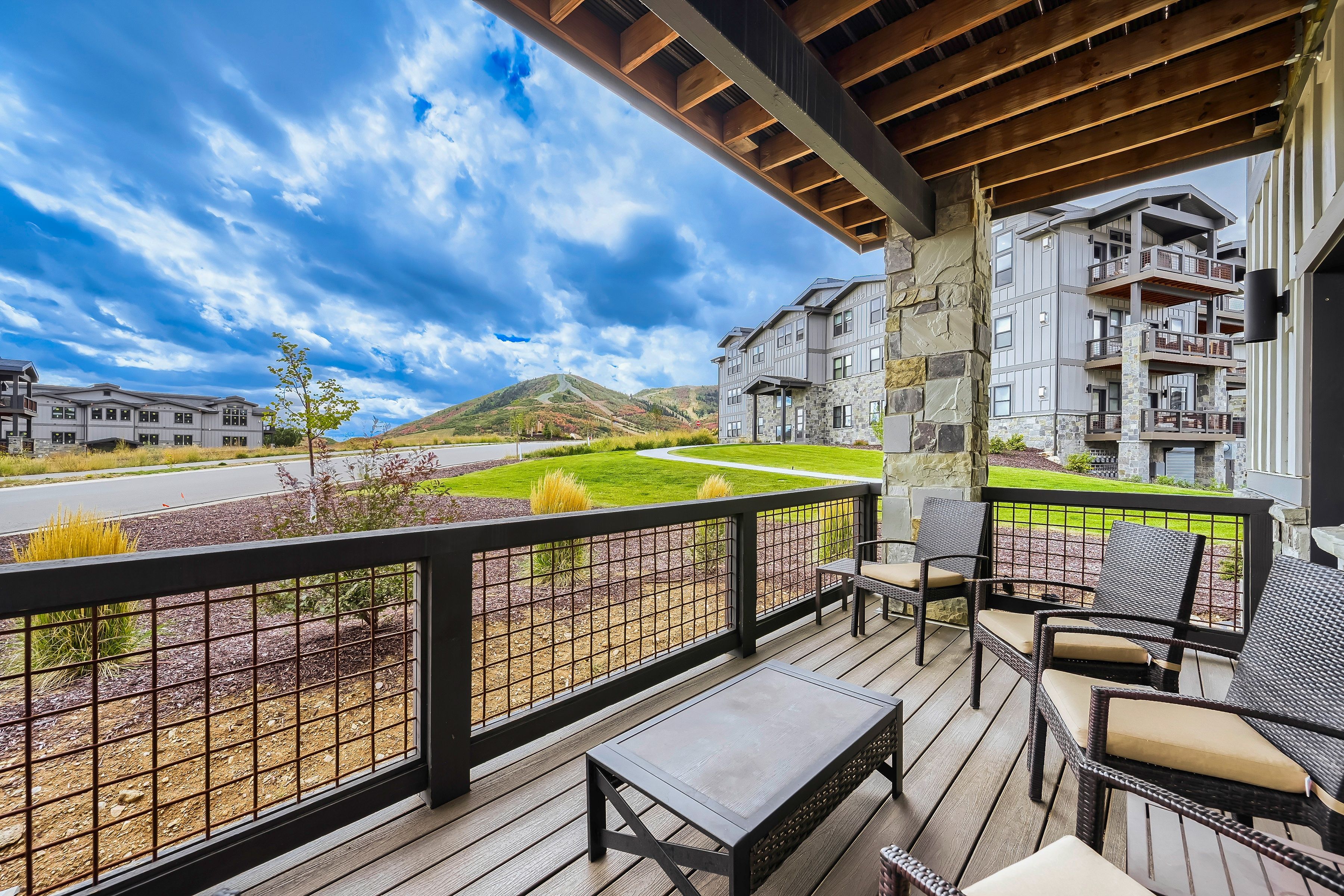 A covered outdoor seating area with a view of a landscaped garden and a mountain in the distance.