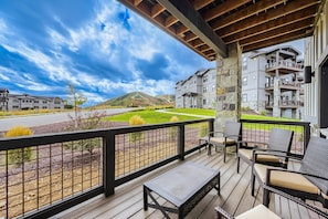 A covered outdoor seating area with a view of a landscaped garden and a mountain in the distance. - Shangri-la 102 3 Bedroom Apts (Heber City)