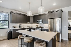 A modern kitchen with a central island, stainless steel appliances, and pendant lighting. - Shangri-la 102 3 Bedroom Apts (Heber City)