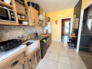 Eine Küche mit Holzschränken, einer Mikrowelle, einem Spülbecken und einer gefliesten Spritzschutzwand.