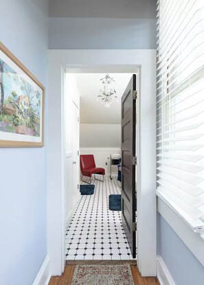 A hallway with a patterned floor, a red chair, and a chandelier. - The Veranda - Sunrise. Sunset. Romance. Historic Pensacola (Pensacola)