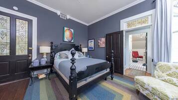 Une chambre à coucher avec un lit, des tables de chevet, une chaise et une porte.