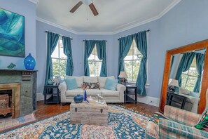 Une pièce avec un canapé, une cheminée, un miroir et un tapis à motifs.