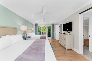 A hotel room with two beds, a dresser, a television, and a view of the outdoors. - Sunny, charming home short walk to beach (Seabrook Island)