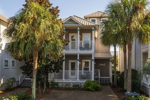 A two-story house with a balcony, surrounded by palm trees and a brick pathway. - 5BR Pet-Friendly Blue Mountain Beach Home | Gulf views & Community Pool (Santa Rosa Beach)