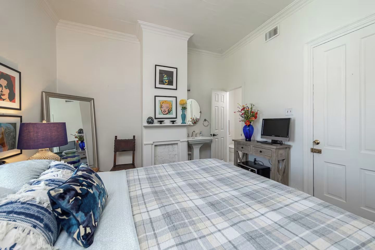 A bedroom with a bed, a dresser, a television, and a mirror.