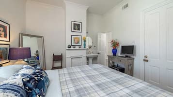 A bedroom with a bed, a dresser, a television, and a mirror.