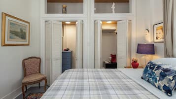 A bedroom with a bed, a chair, a dresser, and a nightstand.