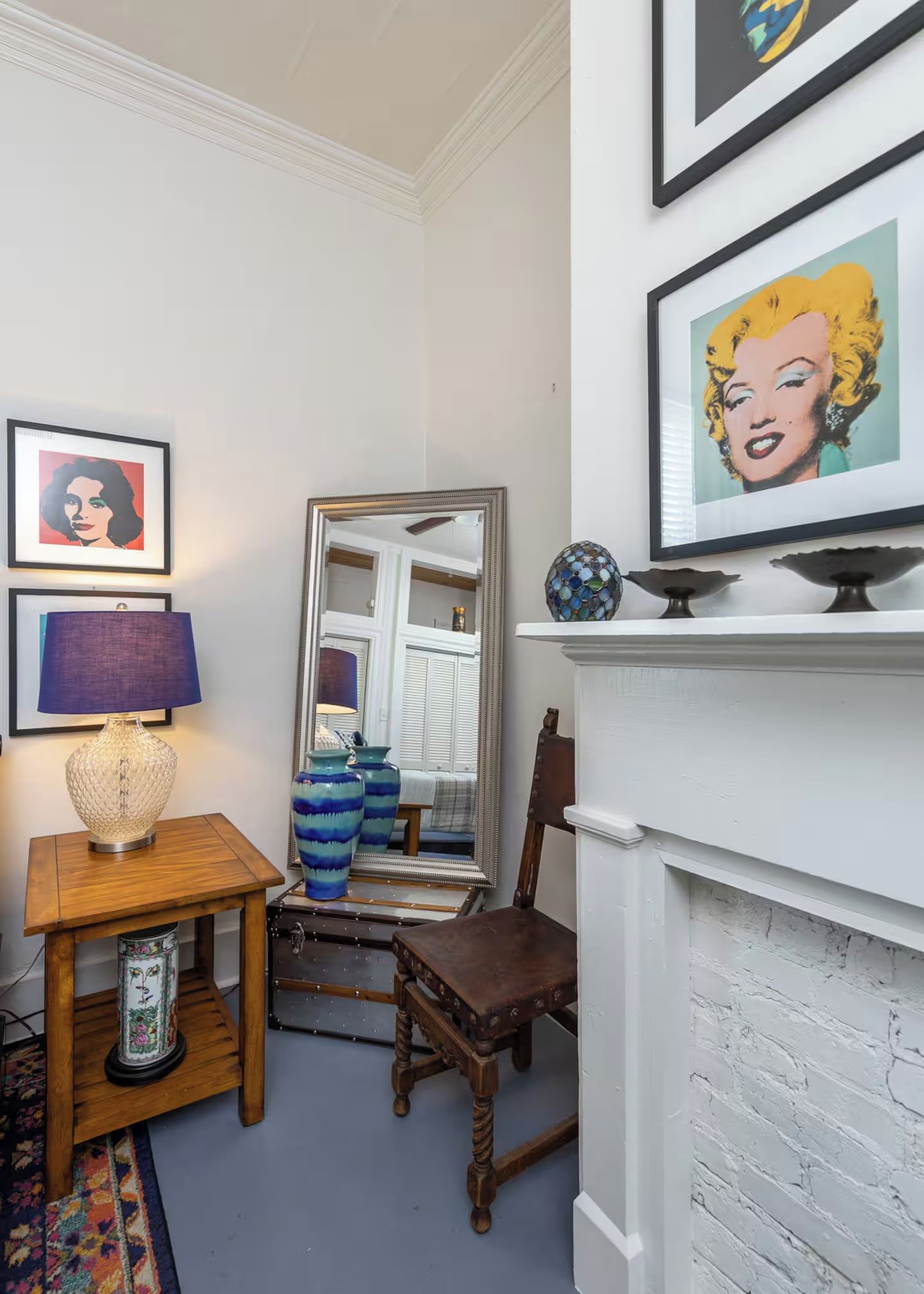 A room with a white fireplace, a mirror, and framed artwork on the wall.