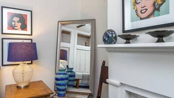A room with a white fireplace, a mirror, and framed artwork on the wall.