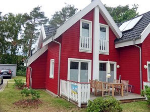 A red house with a white porch, a small deck, and a car parked in the driveway. - Vacation home with a fireplace and infrared sauna, about 800 meters from the sandy beach, washing machine (Glowe)