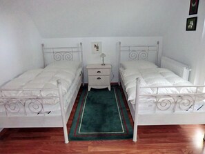 Une chambre double avec deux lits, une table de chevet, une lampe et un tapis vert.