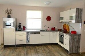 Eine moderne Küche mit weißen Schränken, einem Einbauofen und einem Fenster.
