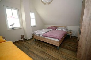 A bedroom with a bed, a window, and a wooden floor. - Vacation home with a fireplace and sauna, about 400 meters from the sandy beach; pets welcome (Glowe)