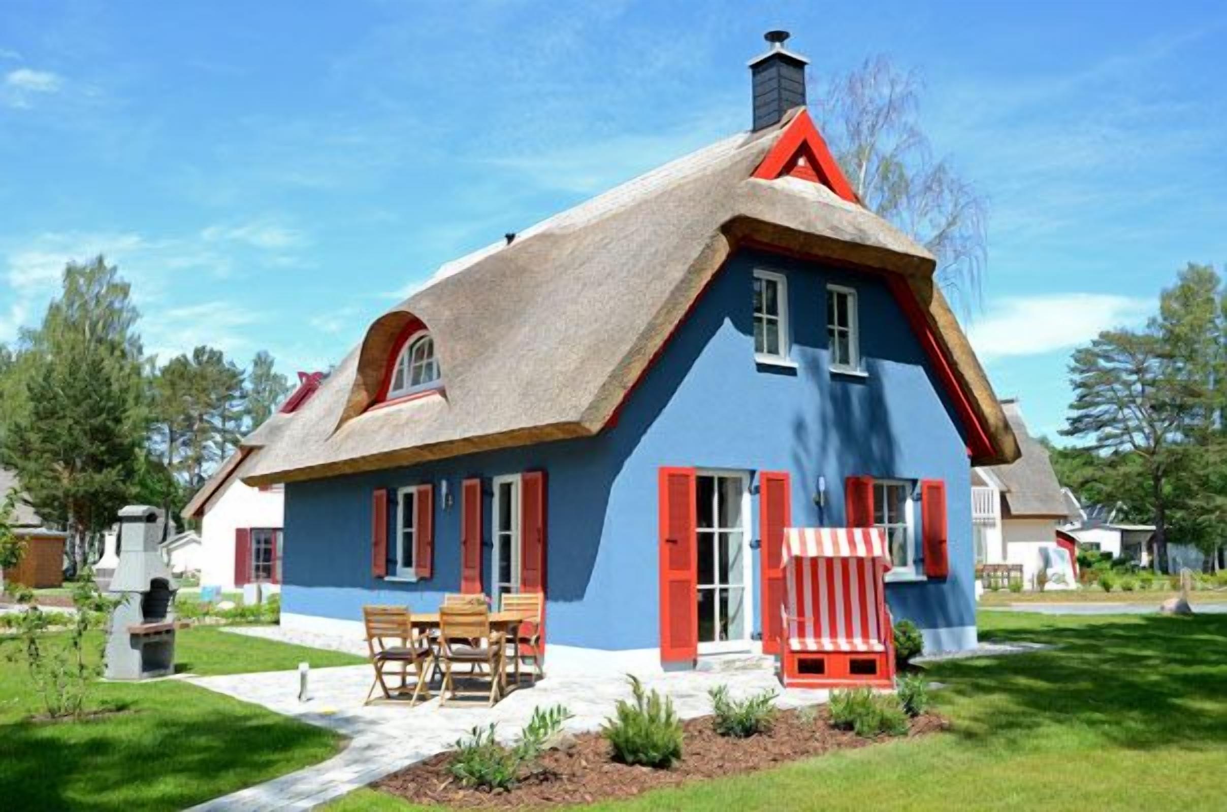 Een huis met een steil dak, een schoorsteen en een veranda met een bank.