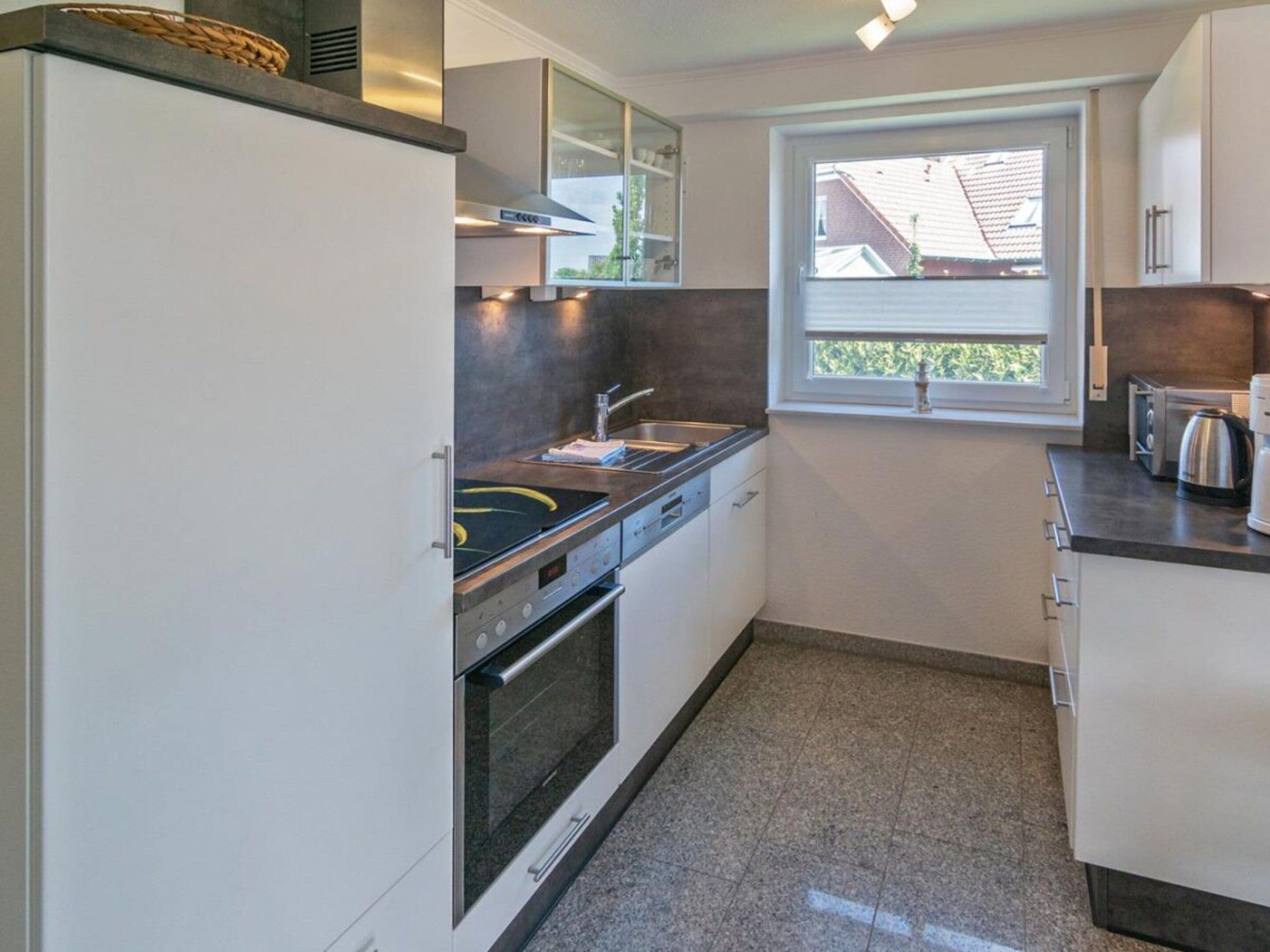 A modern kitchen with a built-in oven, a sink, and a window with a view of the outside.