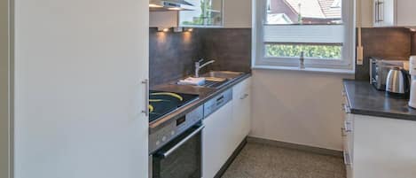 Una cocina moderna con horno empotrado, lavamanos y ventana con vistas al exterior.