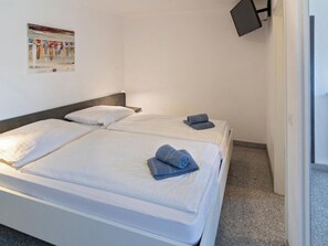 A hotel room with two beds, a flat-screen TV mounted on the wall, and a poster on the wall. - Holiday Home With 2 Bedrooms (Esens)