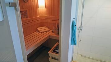 Un sauna avec des bancs en bois et un appareil de chauffage visible.