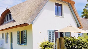 Une maison avec un toit à forte pente, un petit porche et une fenêtre avec des volets.