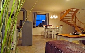 Ein Essbereich mit Tisch und Stühlen, einer Treppe und einem Fenster mit Vorhängen.