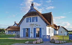 Ein traditionelles Haus mit einem steilen Satteldach, einer weißen Fassade und blauen Fensterläden.