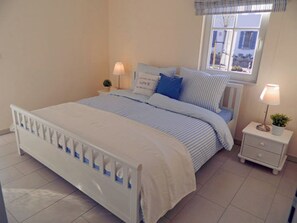 A bedroom with a bed, bedside tables, lamps, and a window. - Vacation home with a fireplace and sauna, about 450 meters from the sandy beach, washing machine, dryer (Glowe)