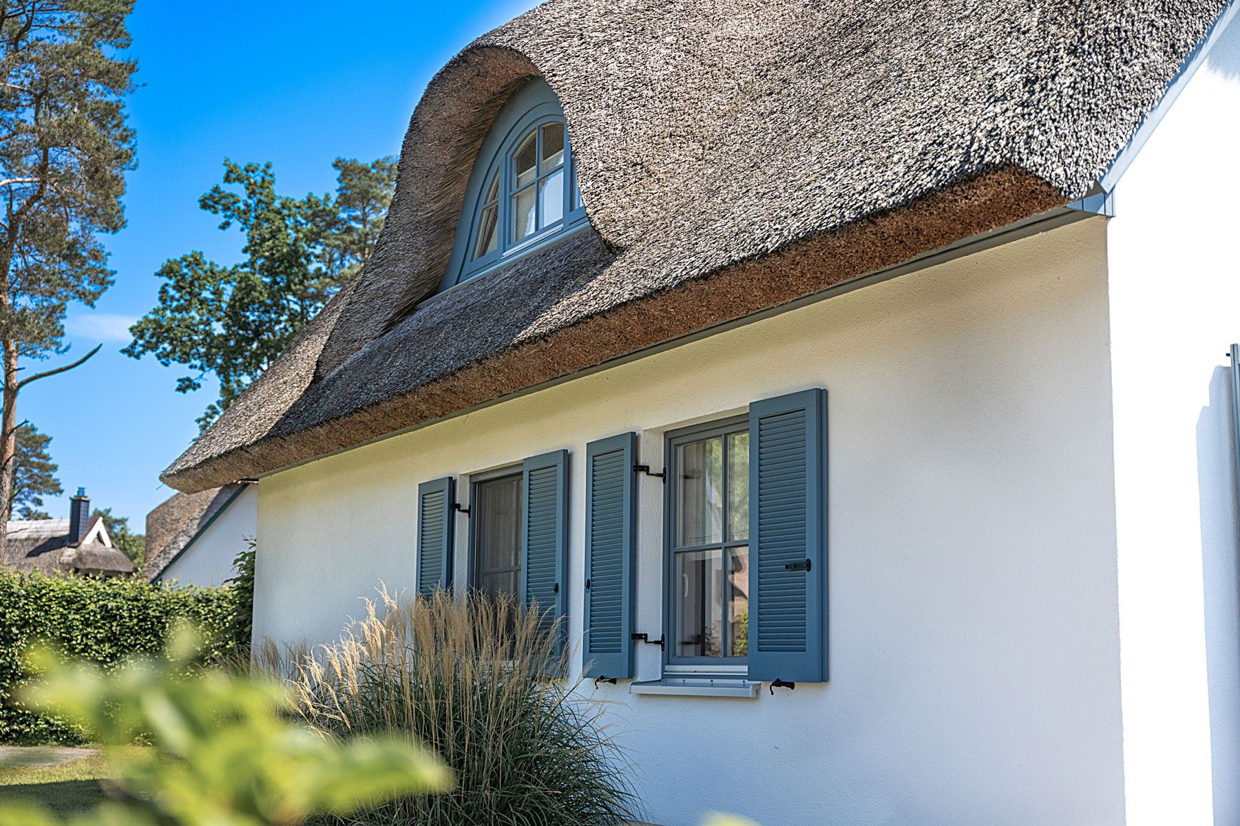 Une maison avec un toit à forte pente, une fenêtre bien visible avec des volets et un ciel dégagé.