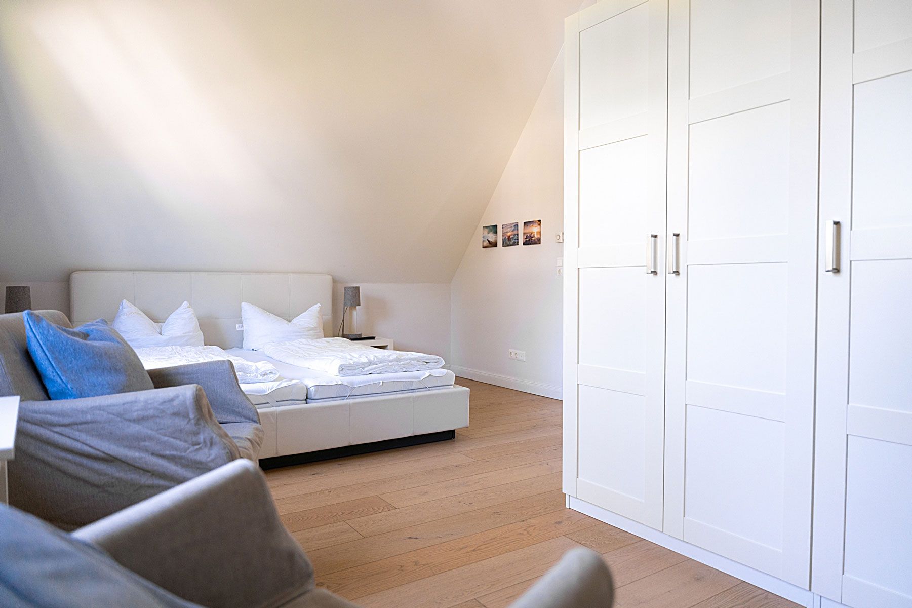 Quarto com cama, mesas de cabeceira, guarda-roupa e sofá.
