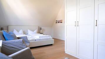 Quarto com cama, mesas de cabeceira, guarda-roupa e sofá.